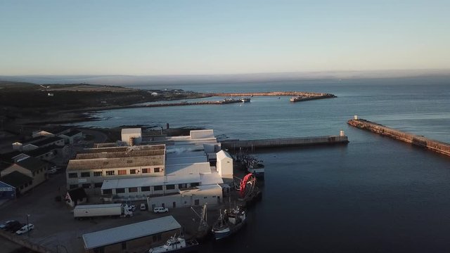 4K summer sunny morning aerial drone video of commercial harbour piers with vessels boats, fishing factory, town panorama, Indian Ocean coast town Gans Bay, Garden Route, Western Cape, South Africa