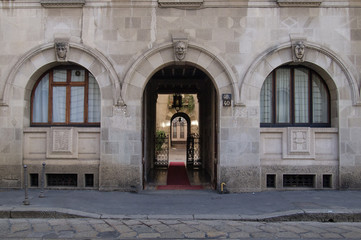 sober fa&ccedil;ade of an old building, arched entrance leading to an elegant arcaded courtyard