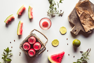 Tasty summer bottled watermelon drink in a basket and slices of fresh fruits on white background