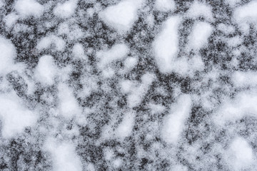 Fresh wet snow on asphalt driveway, as a nature background