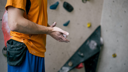 junger Mann in Kletterhalle mit Kreide Magnesium an den Händen