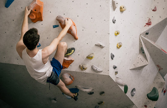 athletischer Mann beim Bouldern an k&uuml;nstlichen Kletteranlage