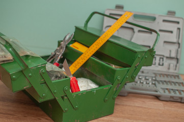 Green metal toolbox on a wooden floor with a green background. Closeup photo with copyspace.