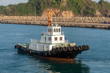 White super structure and black hull tugboat is sailing in the industry port's harbour