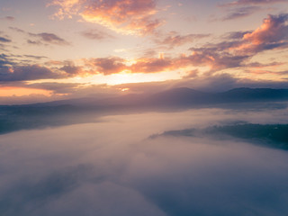 Fototapeta na wymiar aerial view of orange and yellow glorious sunrise landscape with mist and fog over the valley of the small town of jarabacoa dominican republic