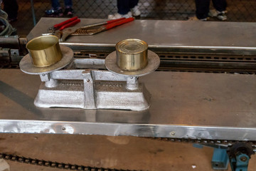 Two golden cans are coming from conveyor in old salmon cannery in Alaska. Fresh fish in the can.