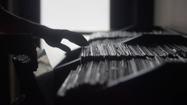 Close-up silhouette of a person inspecting vinyl records in a record store