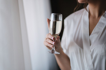 Portrait of gorgeous bride at hotel in morning. Charming woman with glass of champagne