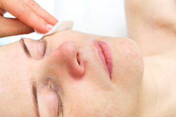 Beautician cleans face. Young woman in a beauty salon. Cosmetology concept. The cosmetologist performs a procedure to cleanse the face with problem skin. Anti age and wrinkle.