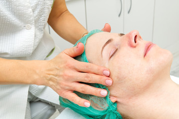 Obraz na płótnie Canvas Beautician applies a natural moisturizing mask to the face of a young beautiful woman. Anti-aging mask and wrinkles for problem skin. Cosmetology concept. The cosmetologist performs the procedure to