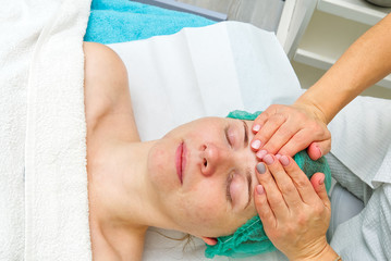 Beautician applies a natural moisturizing mask to the face of a young beautiful woman. Anti-aging mask and wrinkles for problem skin. Cosmetology concept. The cosmetologist performs the procedure to