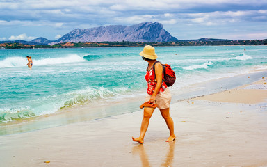 Landscape with girl on La Cinta beach and Mediterranean Sea and Tavolara Island in Sardinia on...