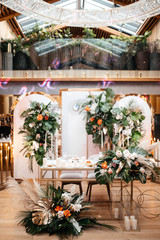Fototapeta na wymiar Wedding table serving. Wedding luxury decor. Wedding presidium for the newlyweds. Beautiful decor with pastel roses, candles and greenery. Indoors