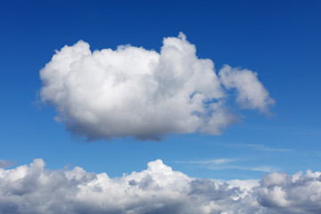 Naklejka na ściany i meble Blauer Himmel mit einer einzelnen Cumuluswolke, die über einer Wolkendecke zu schweben scheint.