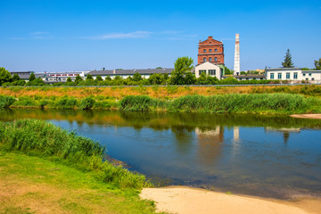 Naklejka premium Historic industrial buildings over the Warta river, at the Nadbrzezna street in the historic quarter of Konin, Poland