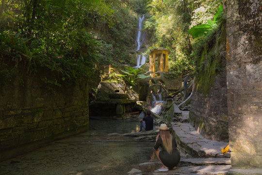 couple taking photos in waterfall in surreal architecture, jungle and waterfalls in the surreal botanical garden of Edward James, Xilitla, San Luis Potosí, Mexico
