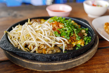 Chinese crispy Oyster omelette serve on hot iron pan on top with fresh bean sprout and chop scallion. 