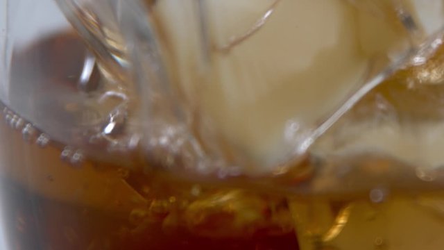 Close up of a whiskey drink being poured over ice, on a white background in studio.