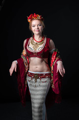 beautiful dancer in traditional folk slavic costume with wreath, vest, skirt, sleeves and necklace with plashmina with flowers ornament looking at camera on black background