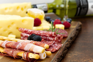 Meat and cheese plate antipasti snack with Prosciutto ham, Parmesan, Blue cheese, Cantaloupe melon and Olives on olive wood serving board on dark background