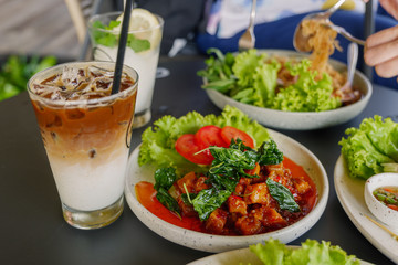 View of ice coffee latte and Thai style Spicy basil with belly pork on black table