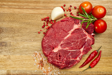 Raw beef steaks on wood board view from above. fresh steak with spices ready for cooking.