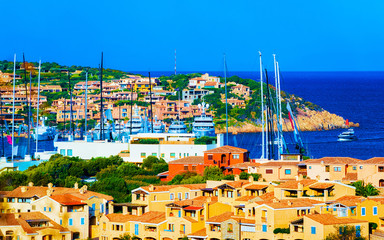 Obraz premium Scenery with Marina and luxury yachts at Mediterranean Sea of Porto Cervo in Sardinia Island of Italy in summer. Landscape View on Sardinian town port with ships and boats in Sardegna. Mixed media.