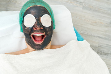 Young woman in a beauty salon with a black mask on her face. The concept of cosmetology. The...