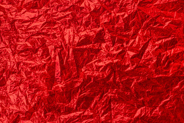 Abstract red shiny festive background. Crumpled red foil texture.