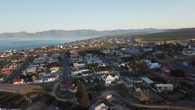 4K summer sunny morning aerial drone video of commercial harbour piers with vessels boats, fishing factory, town panorama, Indian Ocean coast town Gans Bay, Garden Route, Western Cape, South Africa