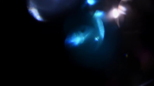 Lens Flare, Abstract Bokeh Lights Moving. Leaking Reflection of a Glass, Crystal, Defocused Shining Colorful rainbow Light Leaks, Rays on Black Background. 4K UHD video, slow motion