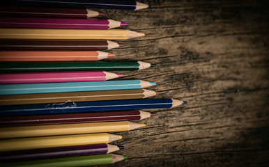 Arrangement of colored pencils on a dark brown wooden table. Cinematic concept to keep on being creative and a way to motivate children to continue their education.