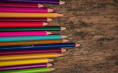 Arrangement of colored pencils on a dark brown wooden table. Cinematic concept to keep on being creative and a way to motivate children to continue their education.