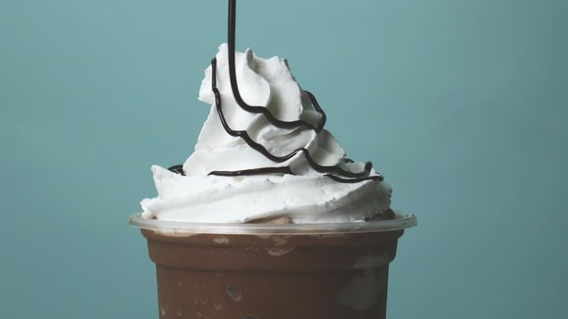 Chocolate topped whip cream on Cocoa smoothie take home cup beverage for summer on blue background,  Food concept Front view.