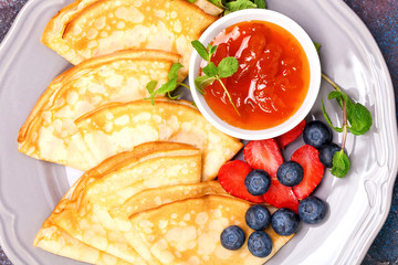 Pancakes with jam and berries on a table. Selective focus. Top view. Copy space.