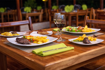 Steak with potatoes and salad accompanied by wine in restaurant