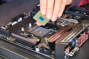 Fototapeta na wymiar Placing a computer chip (CPU) in its socket on a black motherboard. Custom PC build.