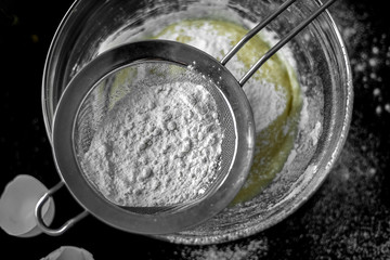 Ingredients for home baking: cookies, bread, cake. Flour, sugar, and eggs are on the black table. Baking dishes.