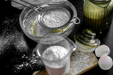 Ingredients for home baking: cookies, bread, cake. Flour, sugar, and eggs are on the black table. Baking dishes.