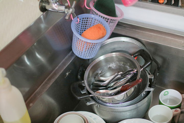 Housewife Washing kitchen ware on the sink hand washing dish or pouring glass with fresh drink water at kitchen faucet while doing cleaning at home