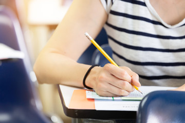 high school,university student study.hands holding pencil writing paper answer sheet.sitting lecture chair taking final exam attending in examination classroom.concept scholarship for education abroad