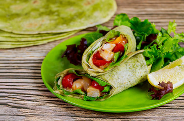Wrap with grilled chicken and vegetable on plate with green salad and lemon.