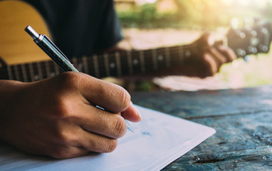 artist songwriter thinking writing notes,lyrics in book at studio.man playing live acoustic guitar...