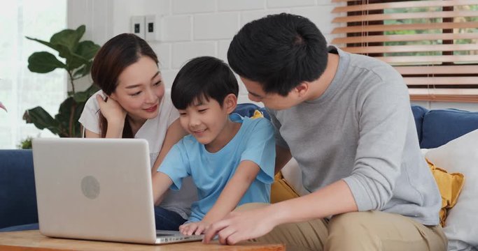 Happy family using laptop together at home. They using computer to watch movie or research information together. Family, Technology and Lifestyle concept.