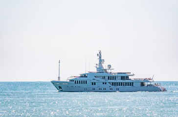 A large white yacht in calm blue sea.