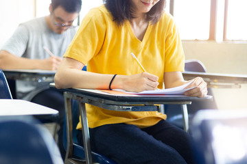 Fototapeta premium high school,university student study.hands holding pencil writing paper answer sheet.sitting lecture chair taking final exam attending in examination classroom.concept scholarship for education abroad