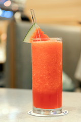 Glass of watermelon smoothie on a table.