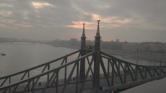 aerial rotating drone shot around the Liberty Bridge in Budapest with a university building in the background on a cloudy winter day