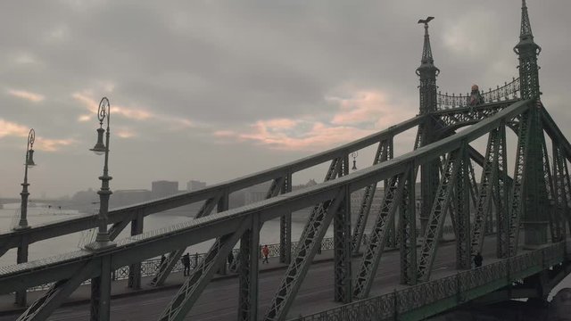 aerial rising drone shot next to the Liberty Bridge in Budapest with a university building in the background on a cloudy winter day