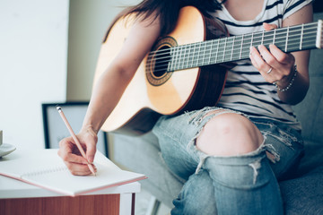 artist songwriter thinking writing notes,lyrics in book at studio.man playing live acoustic guitar...